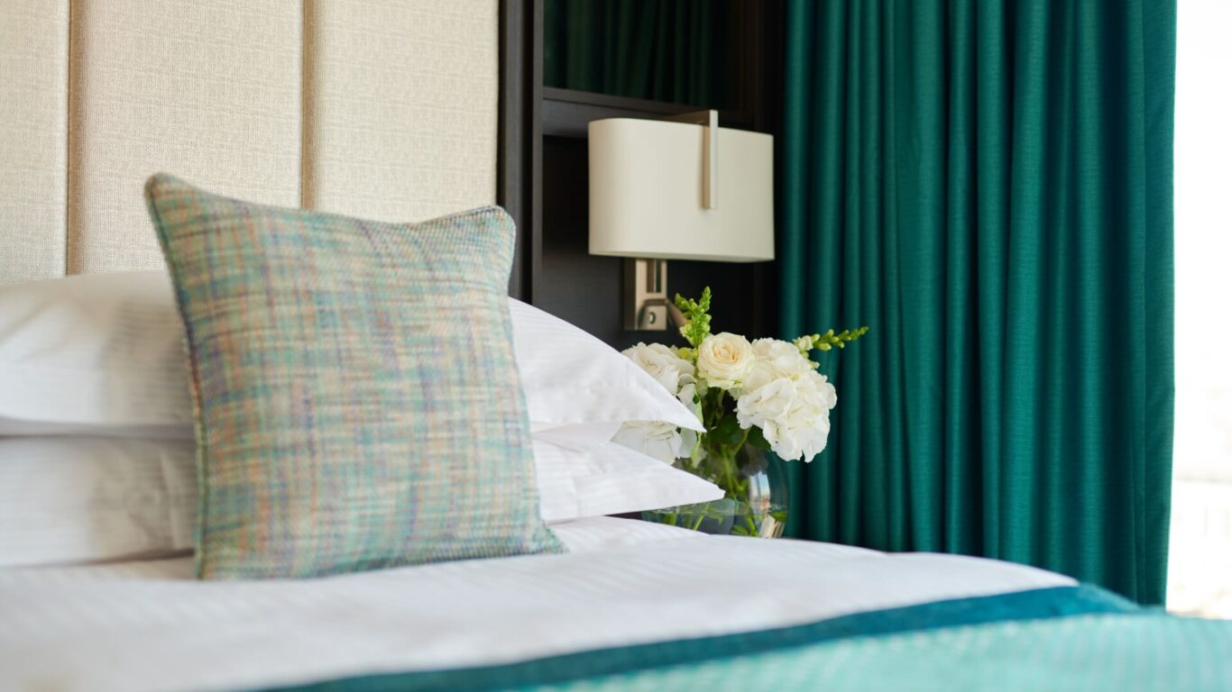 Close up photo of a bed with a bunch of flowers on the sidetable