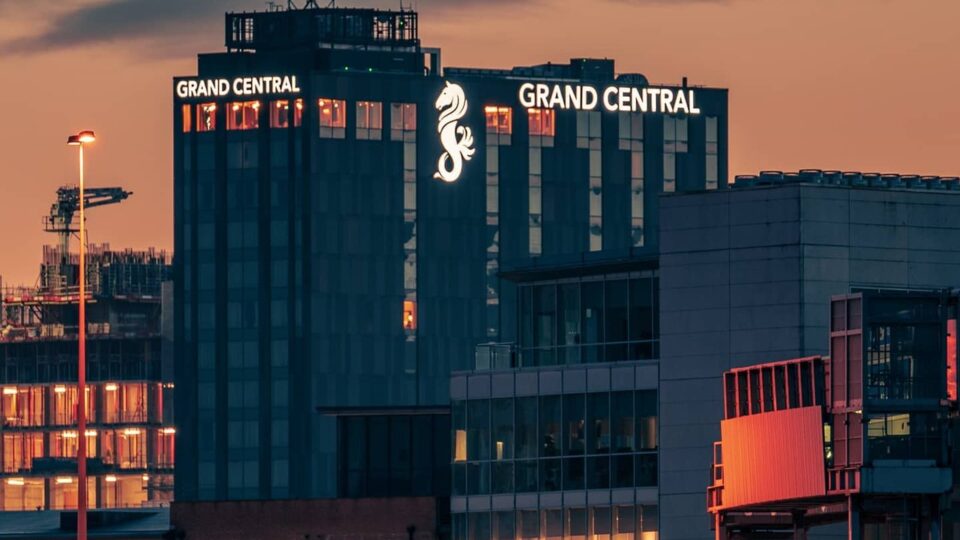 a large building stand out against a sky at dusk, with a large seahorse emblem on the side